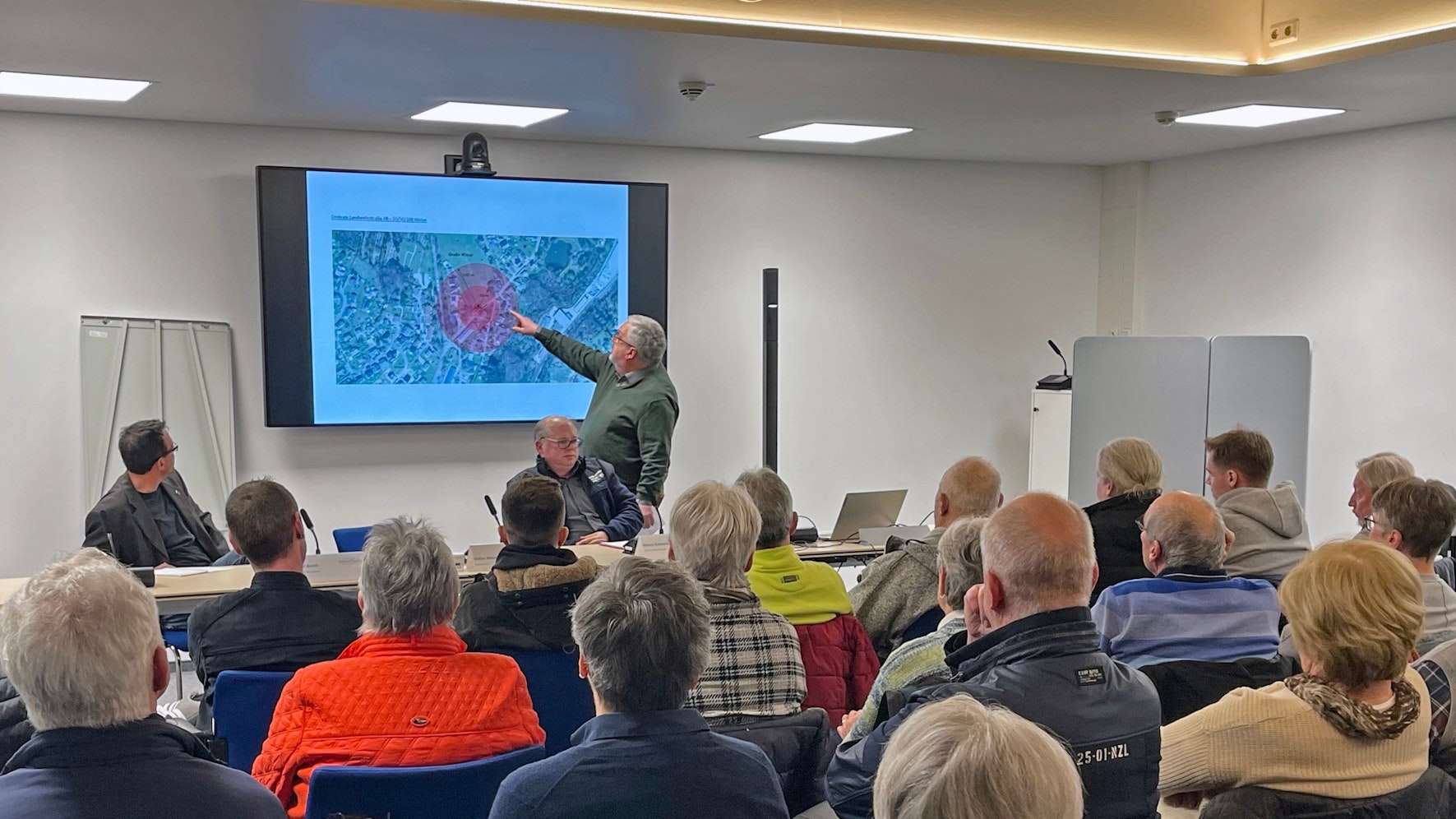 Auf einem Lageplan zeigt Bürgermeister Stefan Meisenberg bei einem Informationsabend den Standort der Container für Geflüchtete.