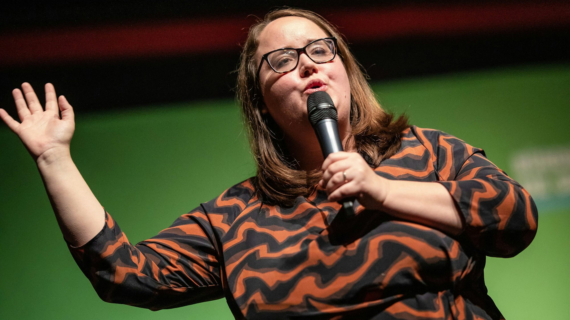 Die Grünen-Vorsitzende Ricarda Lang bei einer Rede zum politischen Aschermittwoch im baden-württembergischen Schorndorf. Lang steht vor einer grünen Wand auf der Bühne.