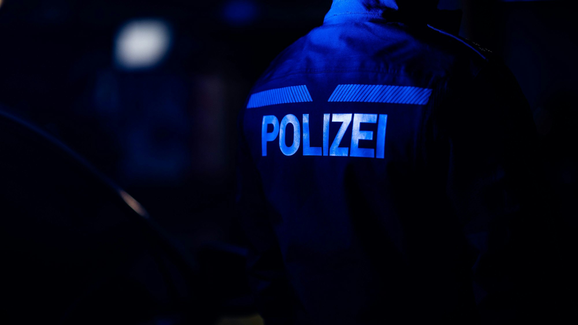 Ein Polizist steht neben einem Polizeiauto.