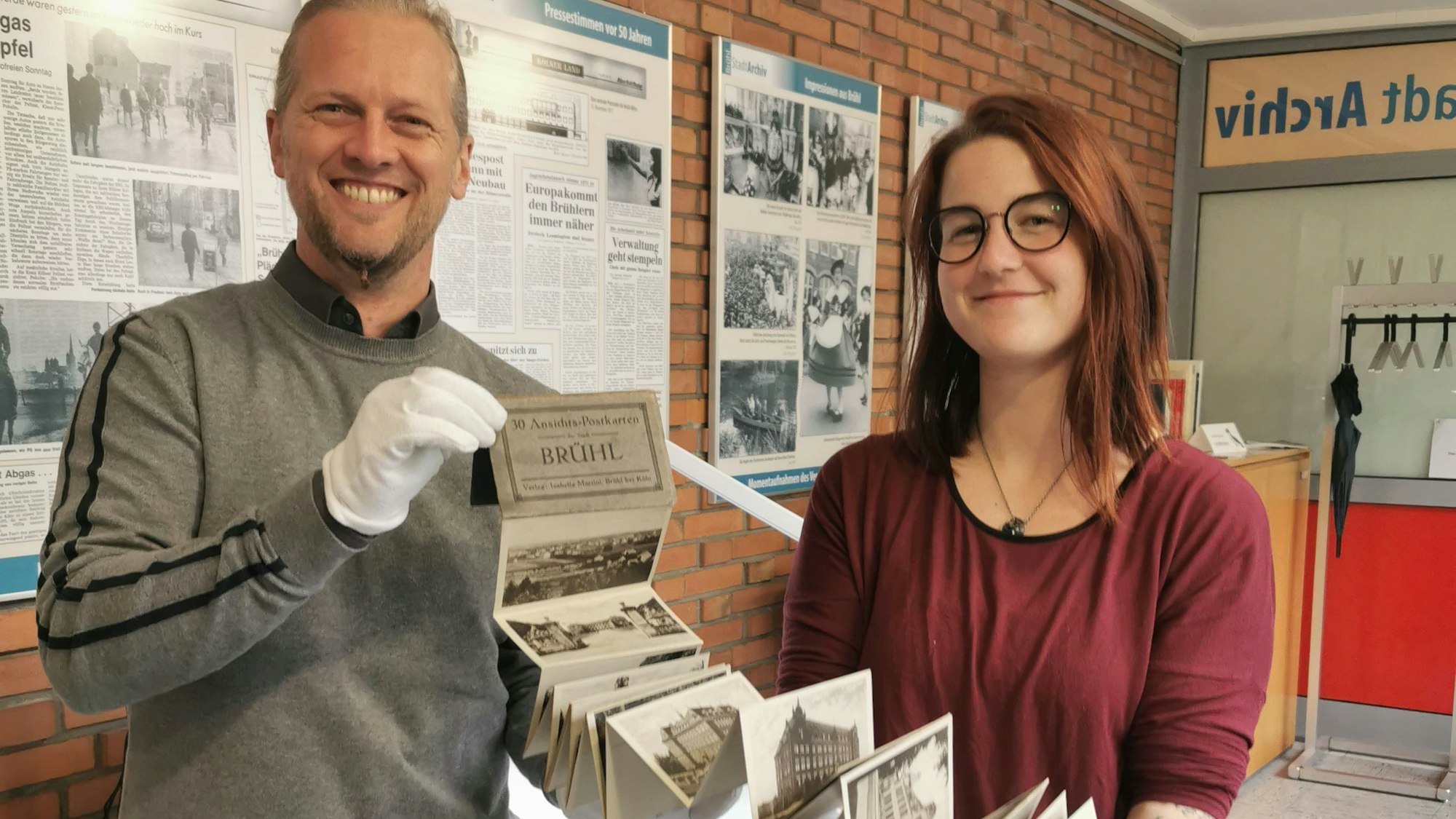 Zu sehen sind zwei Mitarbeiter des Stadtarchiv, die das alte Album in den Händen halten.