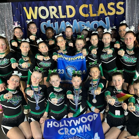 Das Cheerleader-Team und die Trainerinnen strahlen, stolz halten sie ihre Gewinnerringe in die Kamera.