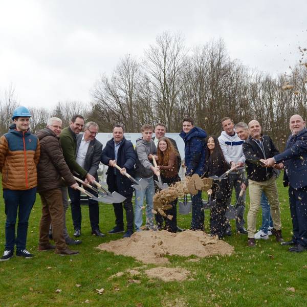 Die Teilnehmerinnen und Teilnehmer werfen mit Spaten Sand in Luft.