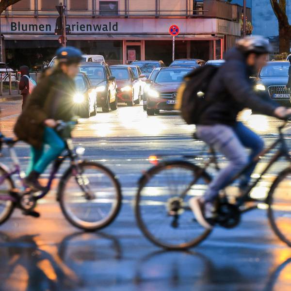 Zwei Fahrradfahrer überqueren hintereinander eine Straße.