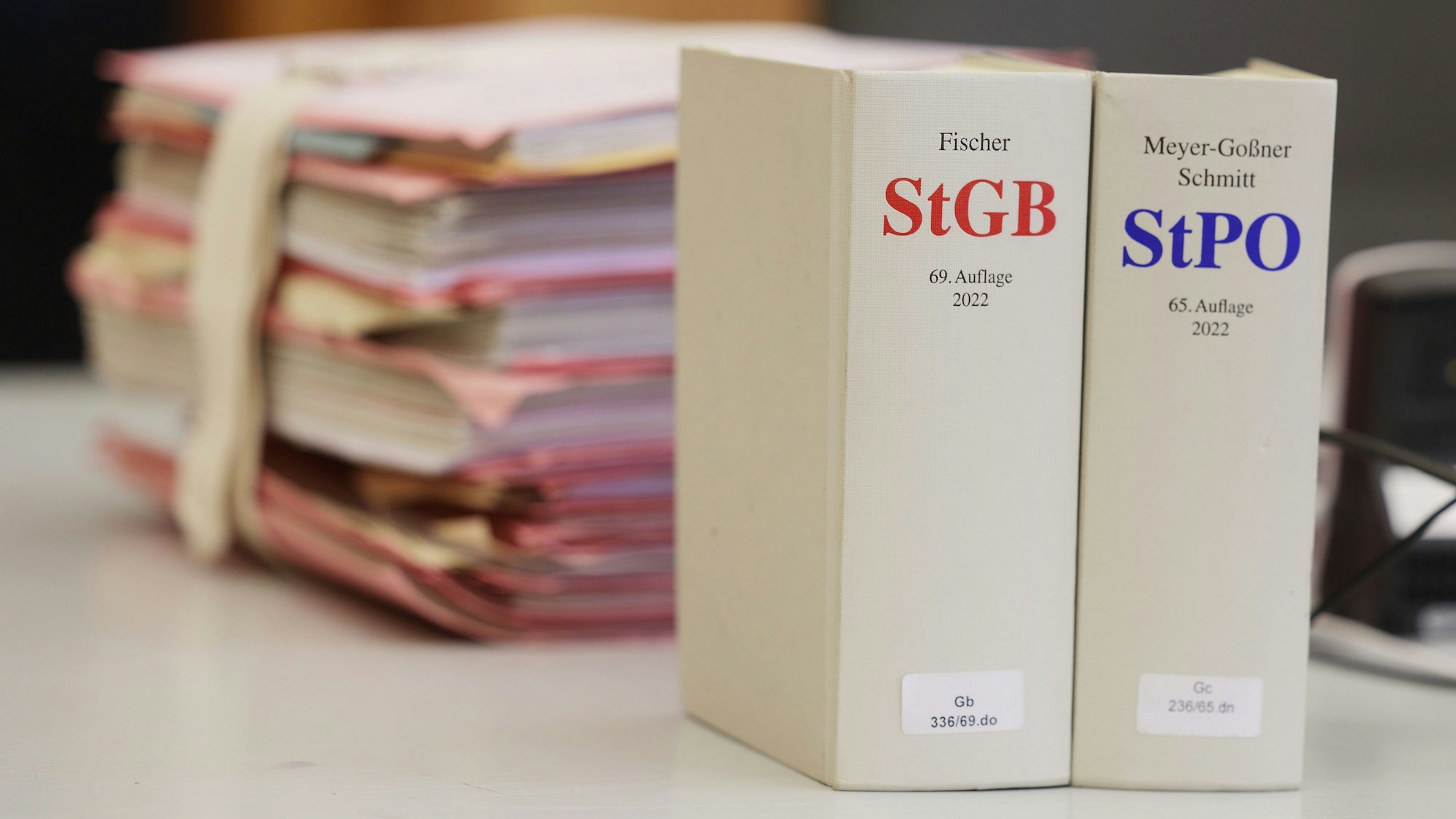 Gerichtsakten und Bücher zu Strafgesetzbuch und Strafprozessordnung liegen bzw. stehen liegen auf einem Tisch in einem Gericht.