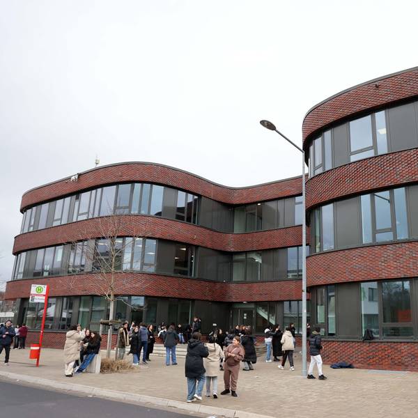 Ein Schulgebäude mit geschwungenen Formen und davor Schülerinnen und Schüler.