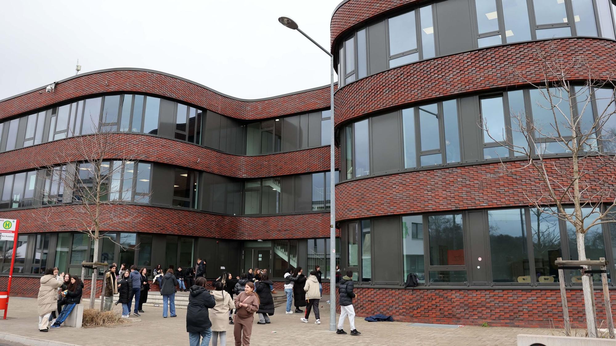 Ein Schulgebäude mit geschwungenen Formen und davor Schülerinnen und Schüler.