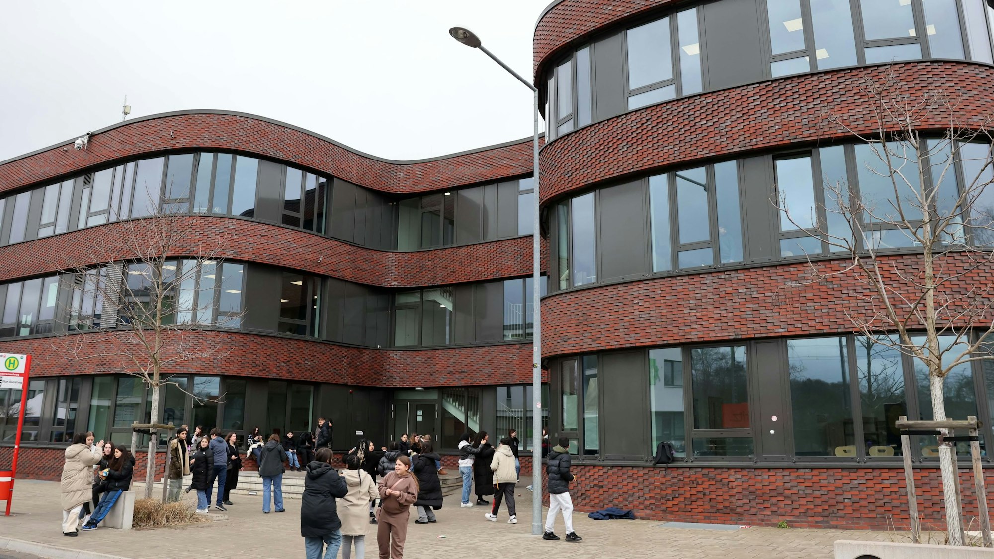 Ein Schulgebäude mit geschwungenen Formen und davor Schülerinnen und Schüler.