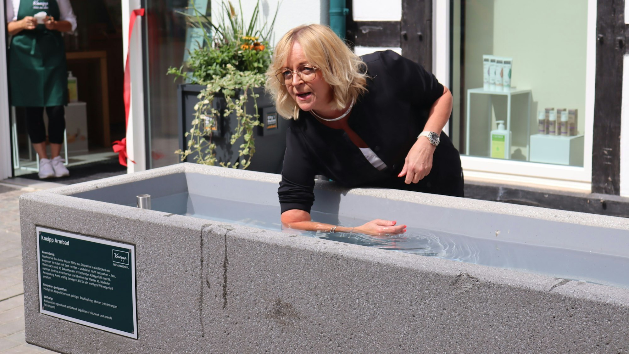 Die Bad Münstereifeler Bürgermeisterin Sabine Preiser-Marian badet ihren Arm in einem Kneippbecken.