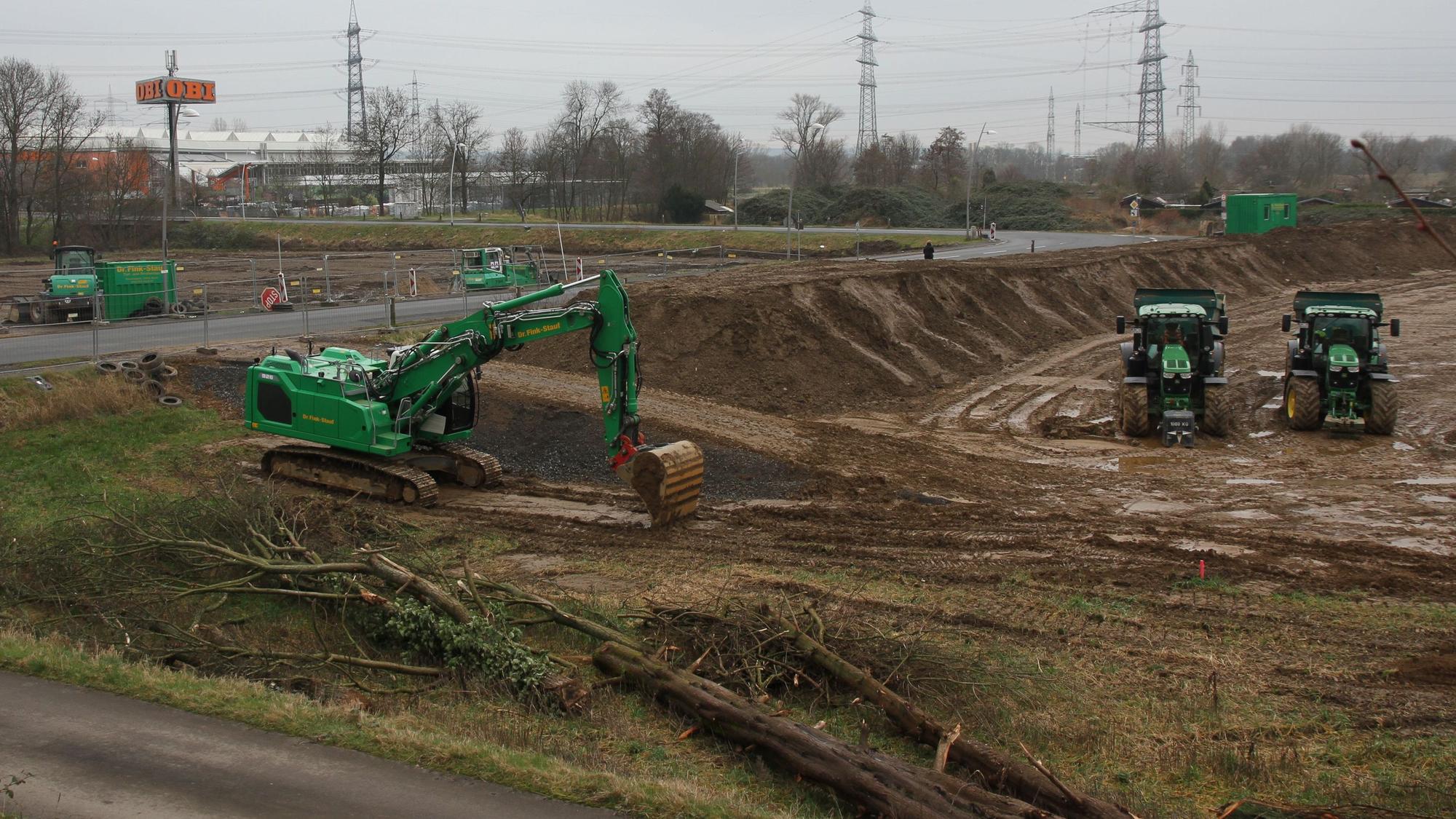 Großbaustelle mit zwei Baugruben sowie grünen Baggern und Traktoren.