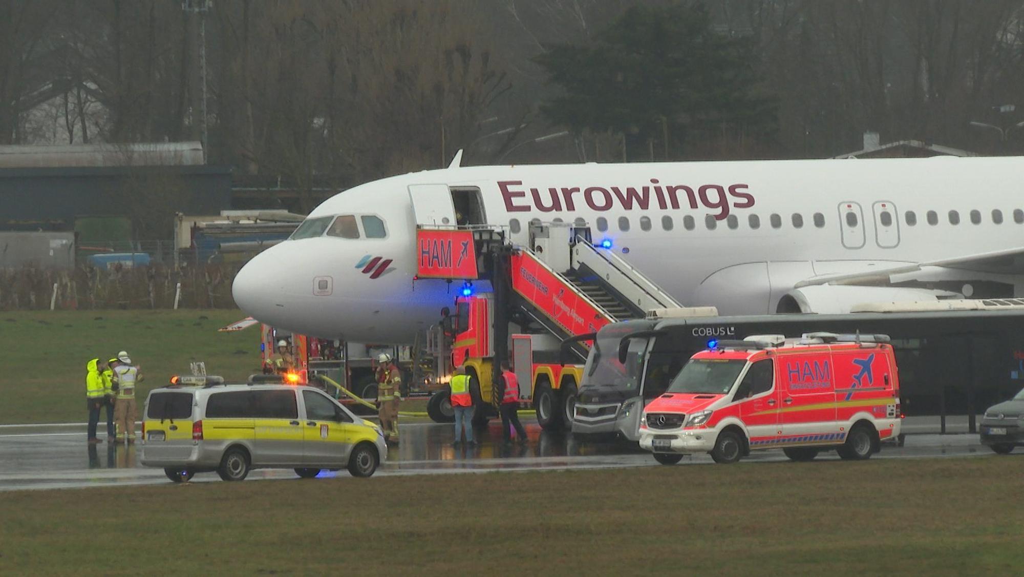 Helfer stehen auf dem Flughafengelände an einem Flugzeug.