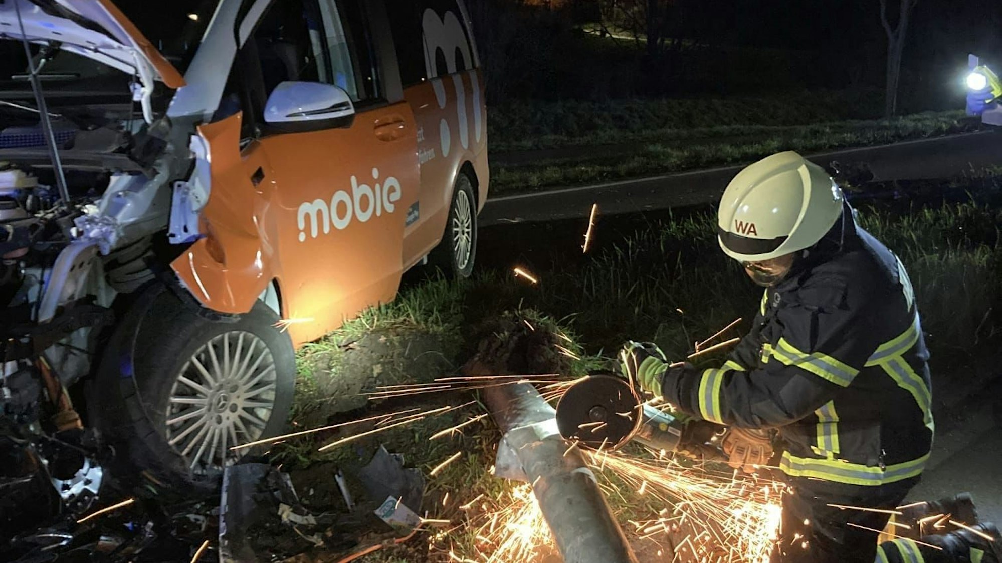 Mit einer Flex durchtrennt ein Feuerwehr den Laternenmast, Funken sind zu sehen.