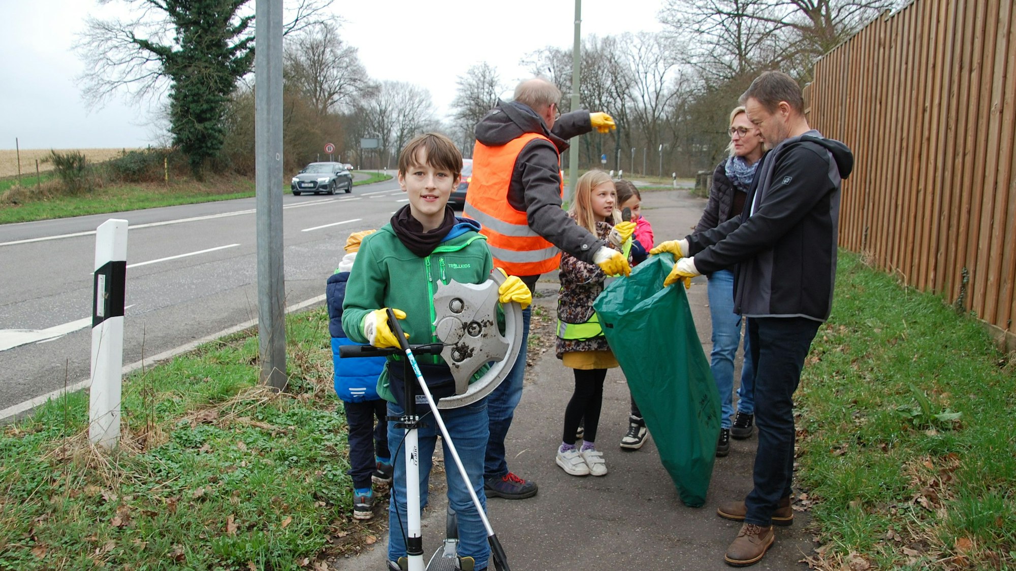 Ein Kind mit einer abgebrochenen Radkappe in der Hand und weitere Müllsammler.