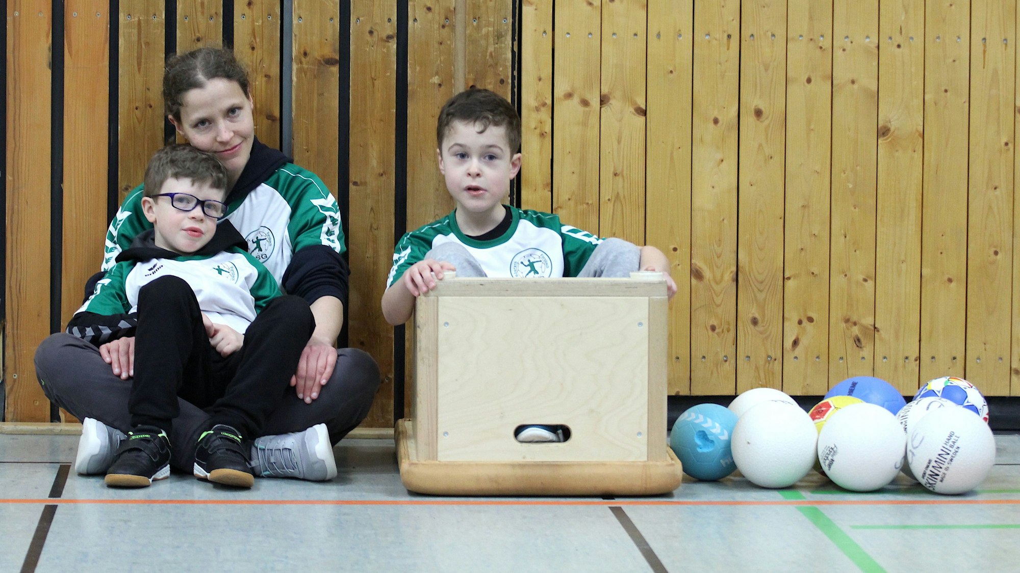 Ein Junge sitzt bei der Trainerin auf dem Schoß, ein anderer hat sich in eine umgedrehte Box gesetzt.