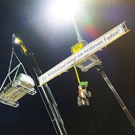 Traktoren, ein Pritschenwagen und ein Pkw schwebten während einer Kundgebung an Kranauslegern.