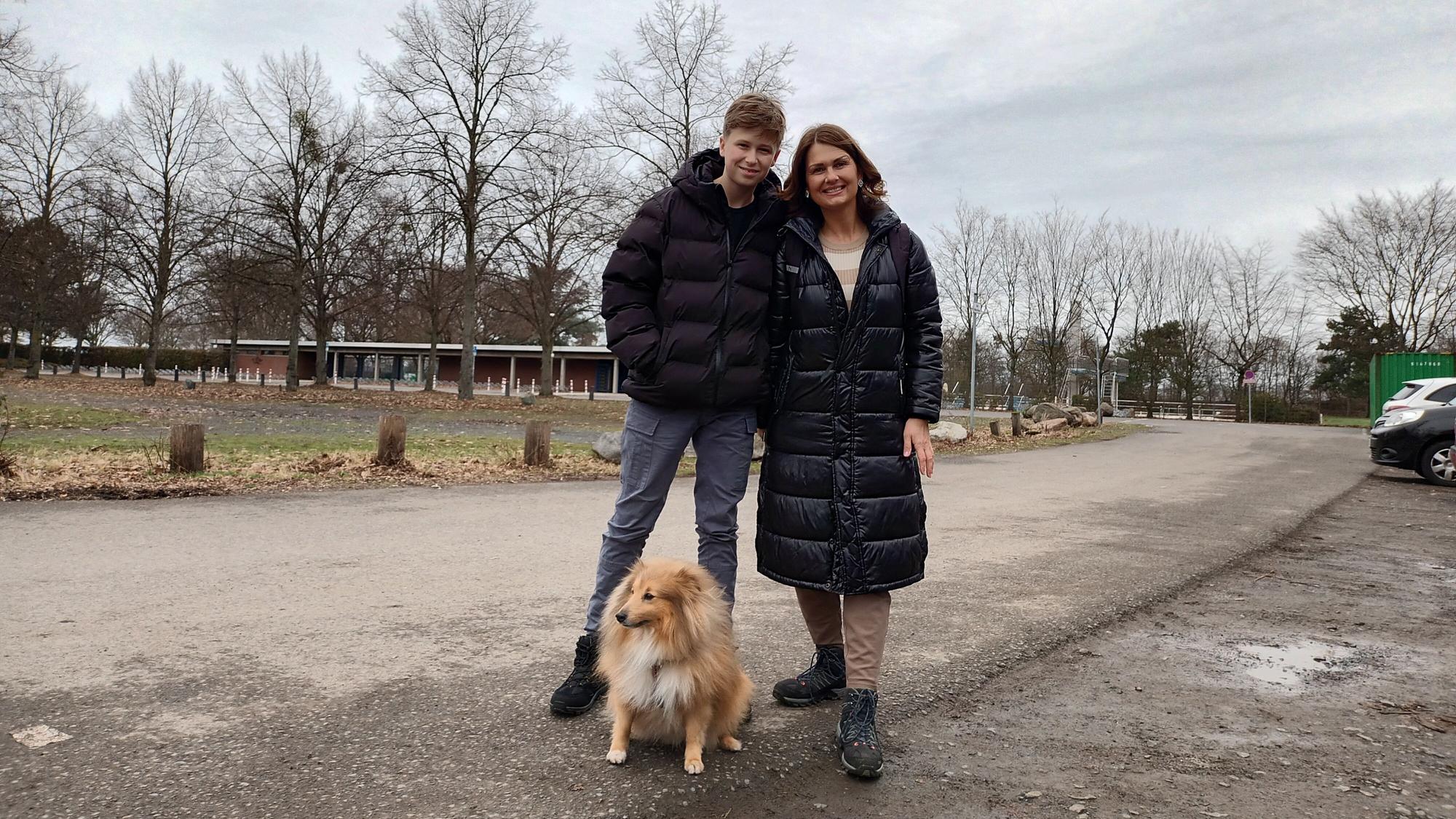 Frau mit Sohn und Hund auf einem Spazierweg