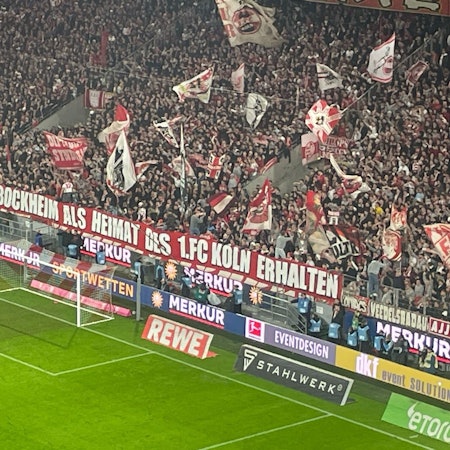 FC-Fans in der Südkurve des Rheinenergie-Stadions zeigen ein Banner mit der Aufschrift: „Geißbockheim als Heimat des 1. FC Köln erhalten“