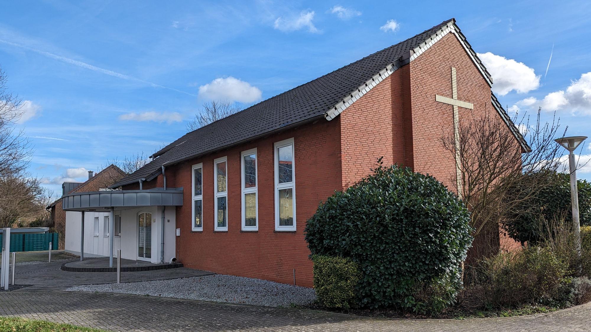 Die kleine Neuapostolische Kirche mit großem Kreuz an der Giebelwand und dem neugestalteten Eingangsbereich.