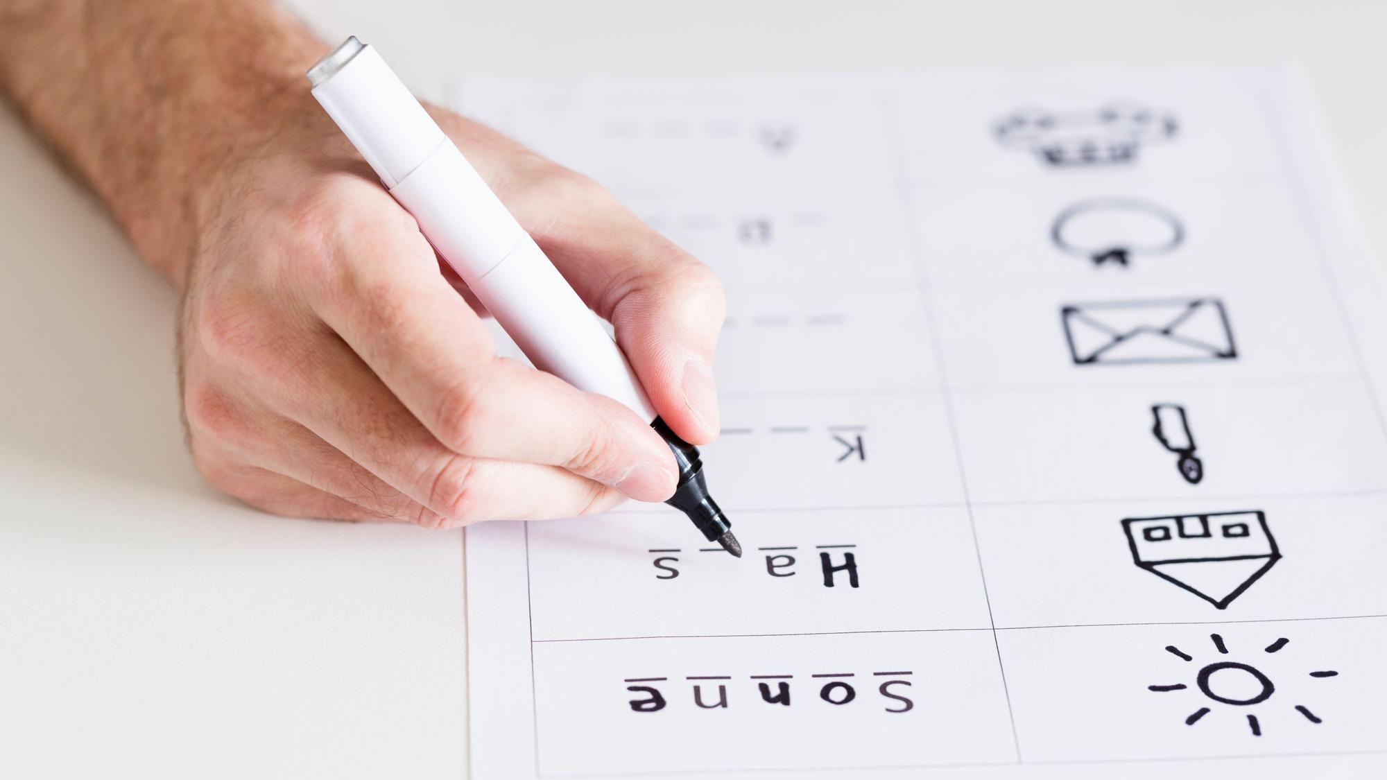 eine Hand füllt mit einem schwarzen Stift einen Lückentext aus