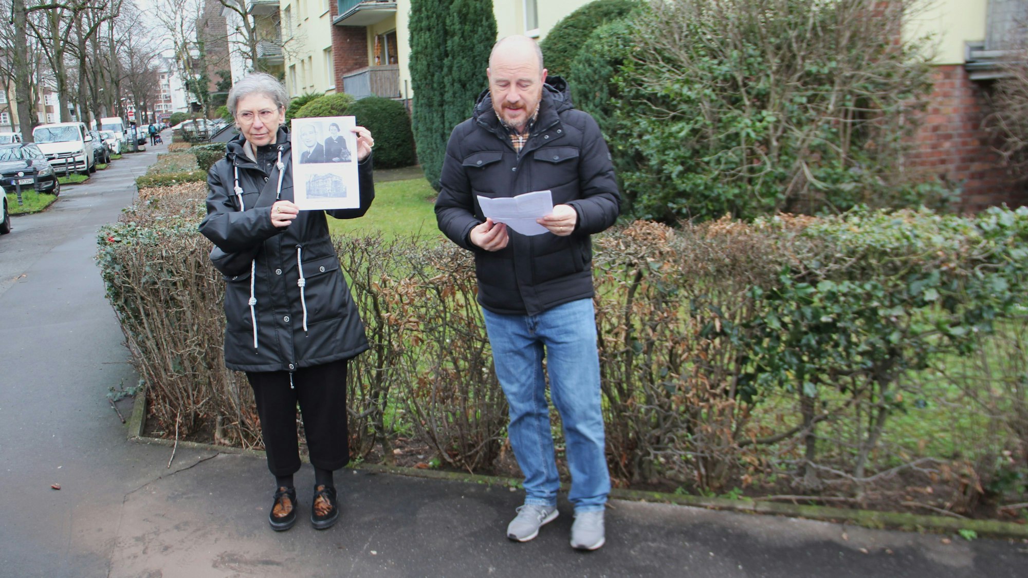Eine Frau hält ein Bild hoch, ein Mann liest von einem Blatt ab.