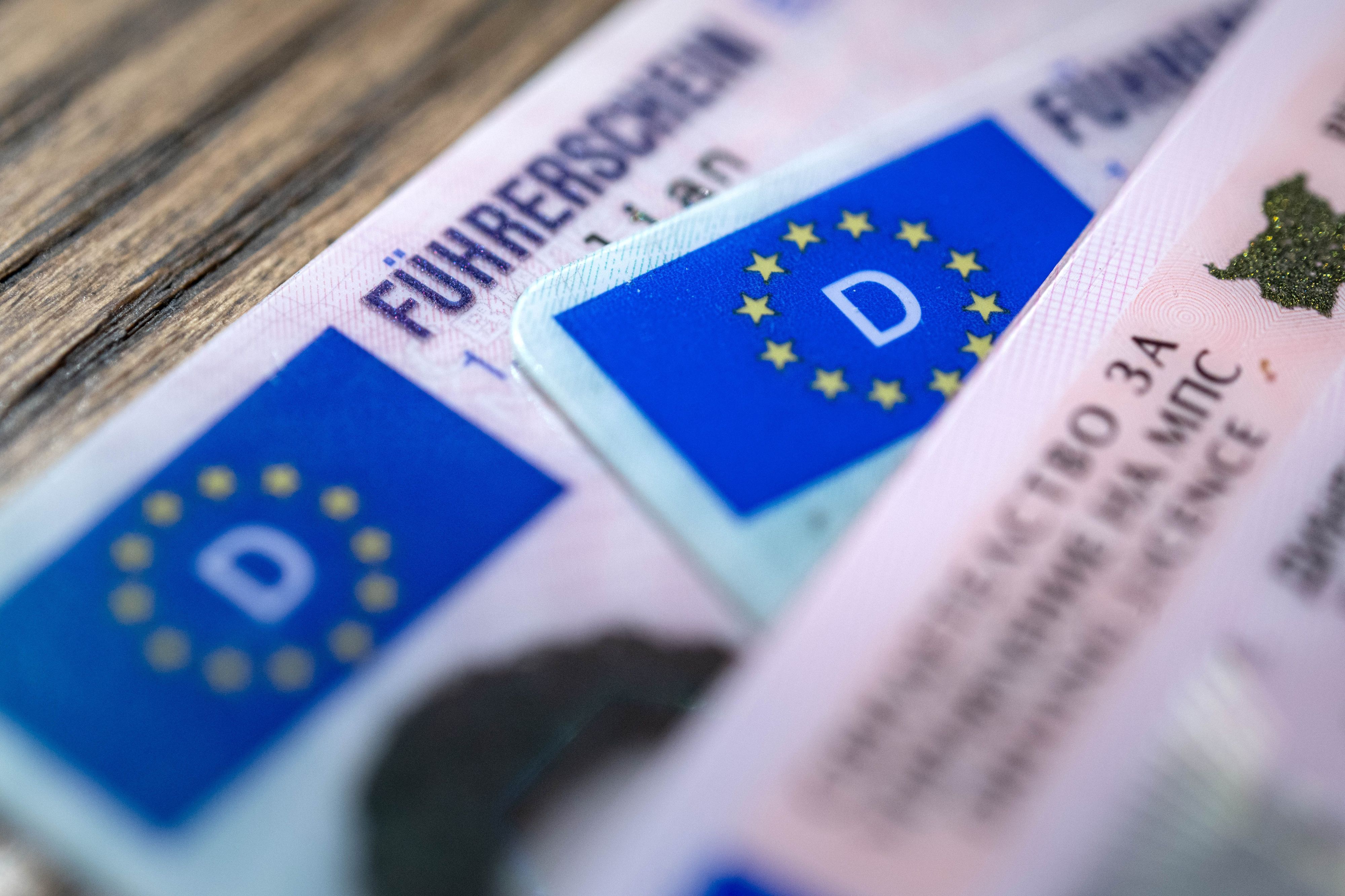 ARCHIV - 06.12.2023, Bremen: ILLUSTRATION - Ein bulgarischer und zwei deutsche Führerscheine liegen auf einem Tisch. Der Verkehrsausschuss im EU-Parlament stimmt über Vorschläge zu neuen EU-Führerscheinregeln ab. (zu dpa: «EU-Parlament stimmt Position zu EU-weitem Führerscheinentzug ab») Foto: Sina Schuldt/dpa +++ dpa-Bildfunk +++