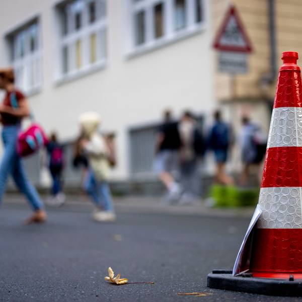 Pylonen stehen auf der Straße an einer Schule.