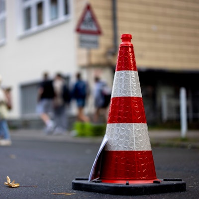 Pylonen stehen auf der Straße an einer Schule.