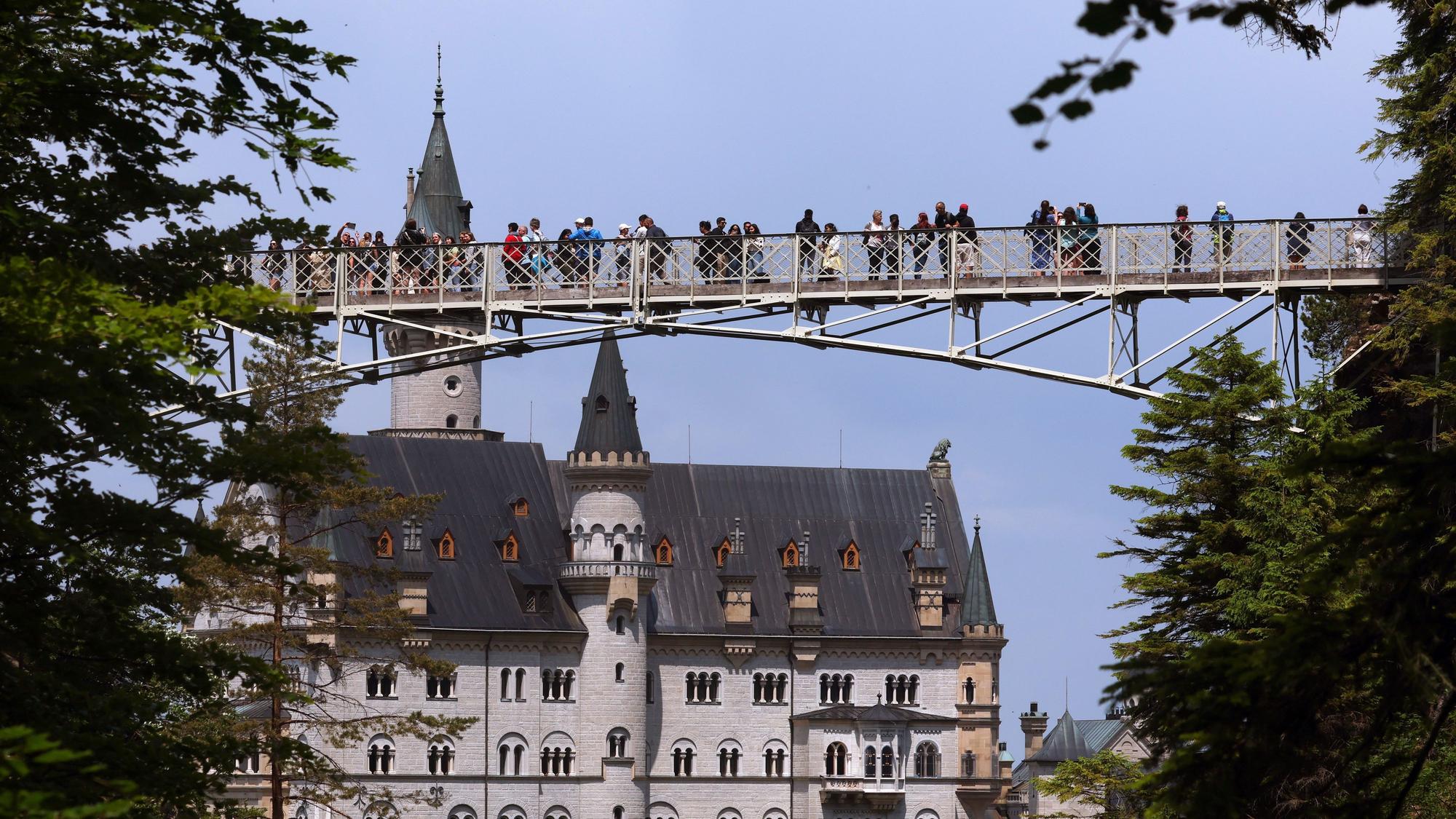 Touristen stehen auf der Marienbrücke vor dem Schloss Neuschwanstein.