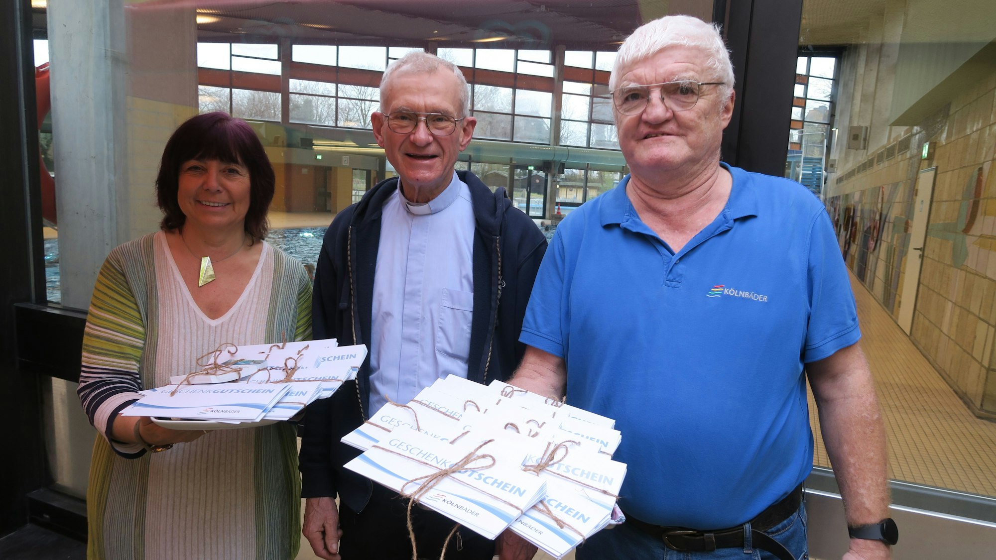 Zwei Männer und eine Frau halten Gutscheine in der Hand.