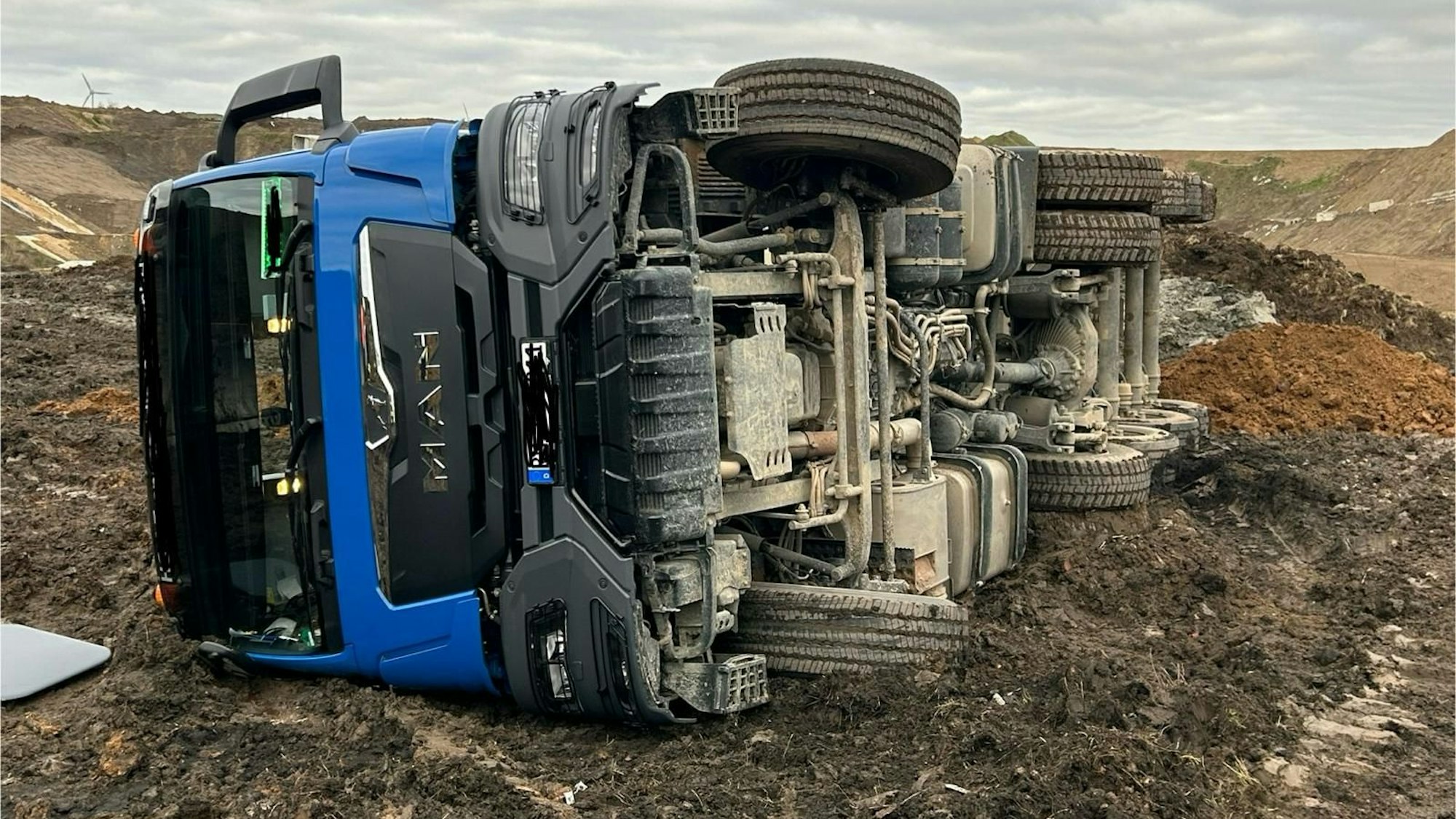 Auf dem Foto ist der umgekippte blaue Sattelschlepper zu sehen.