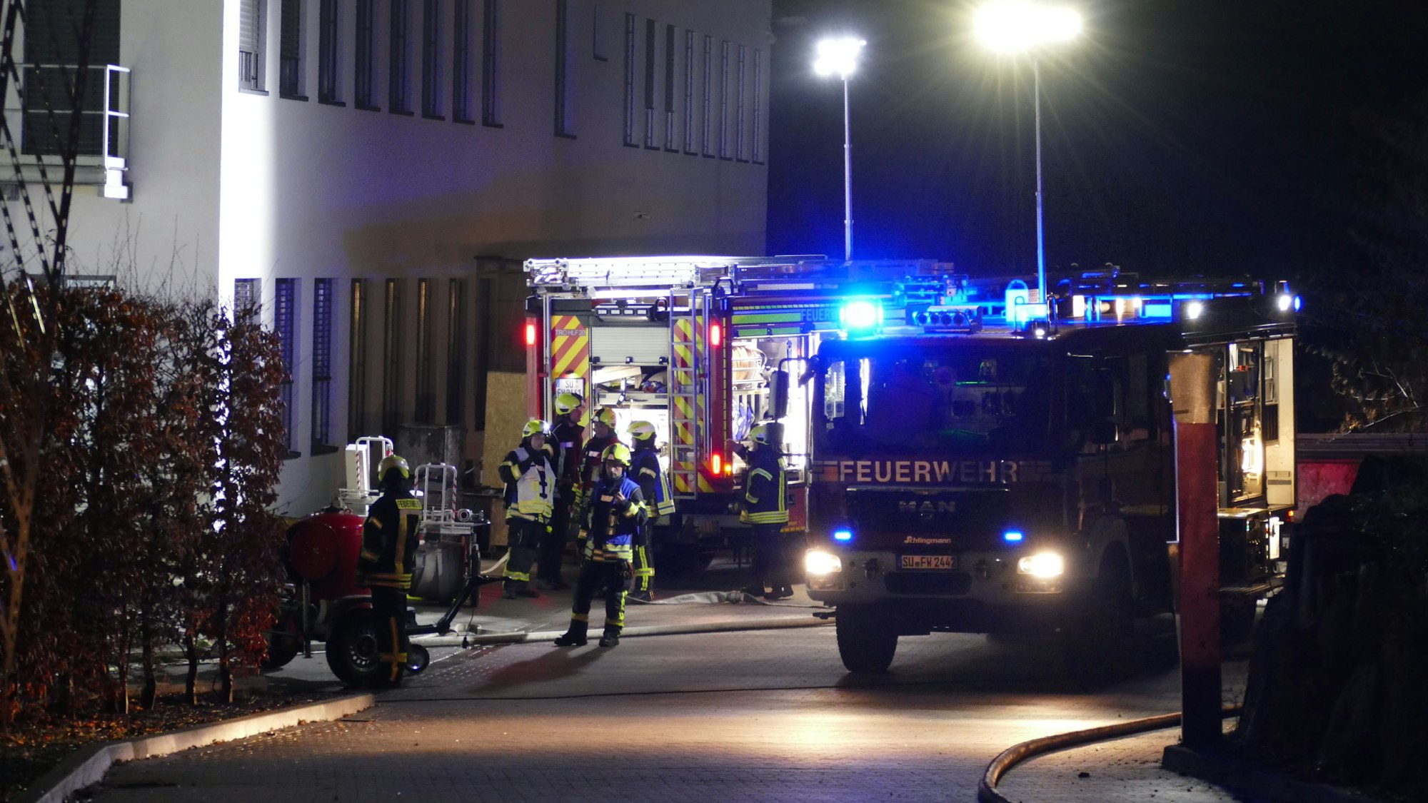 Feuerwehrfahrzeuge und Feuerwehrleute stehen umher.
