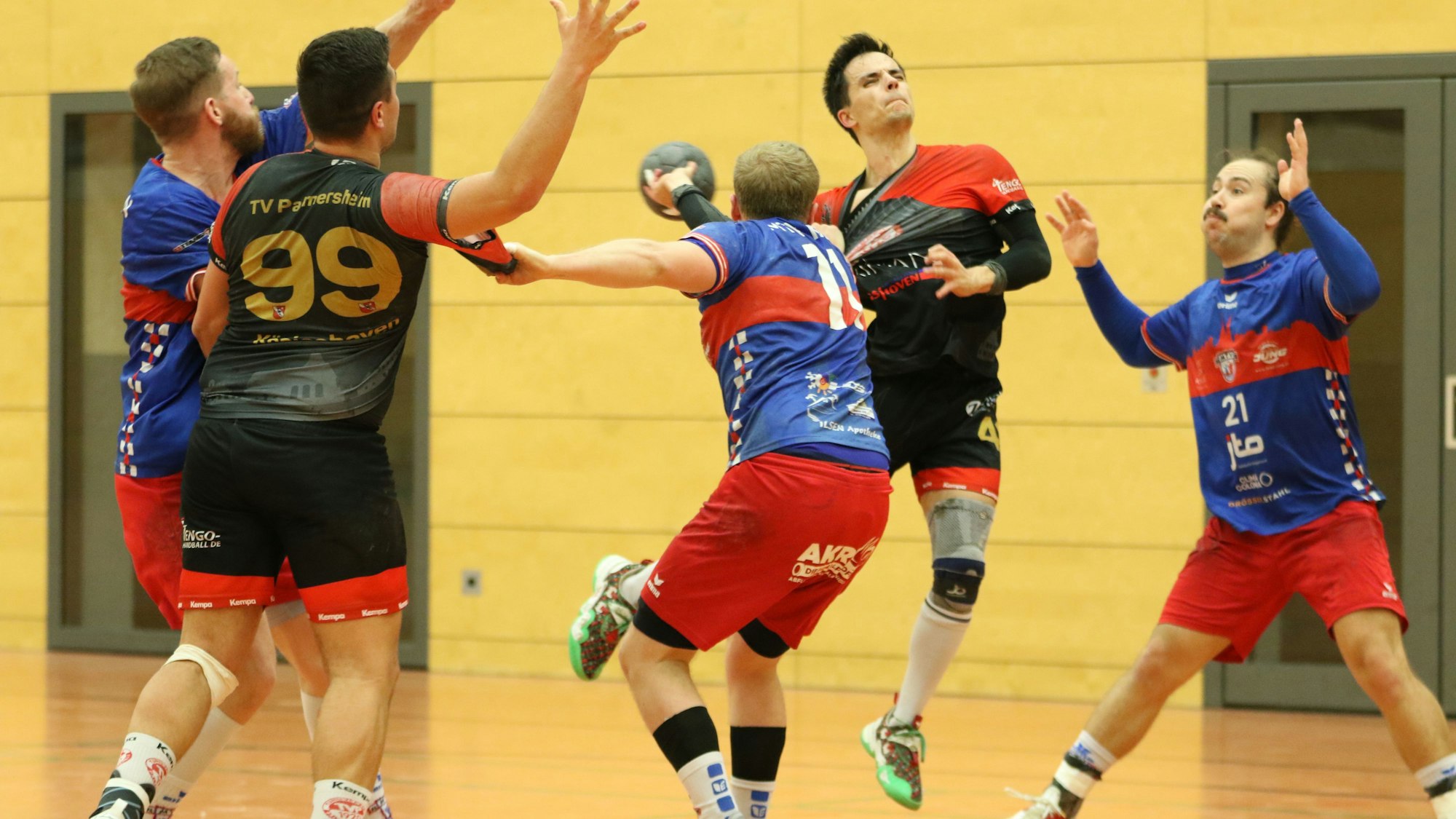 Niklas Grevelding setzt zum Wurf an und wird von einem Gegenspieler am Trikot gezogen. Drei weitere Spieler stehen in der Nähe.