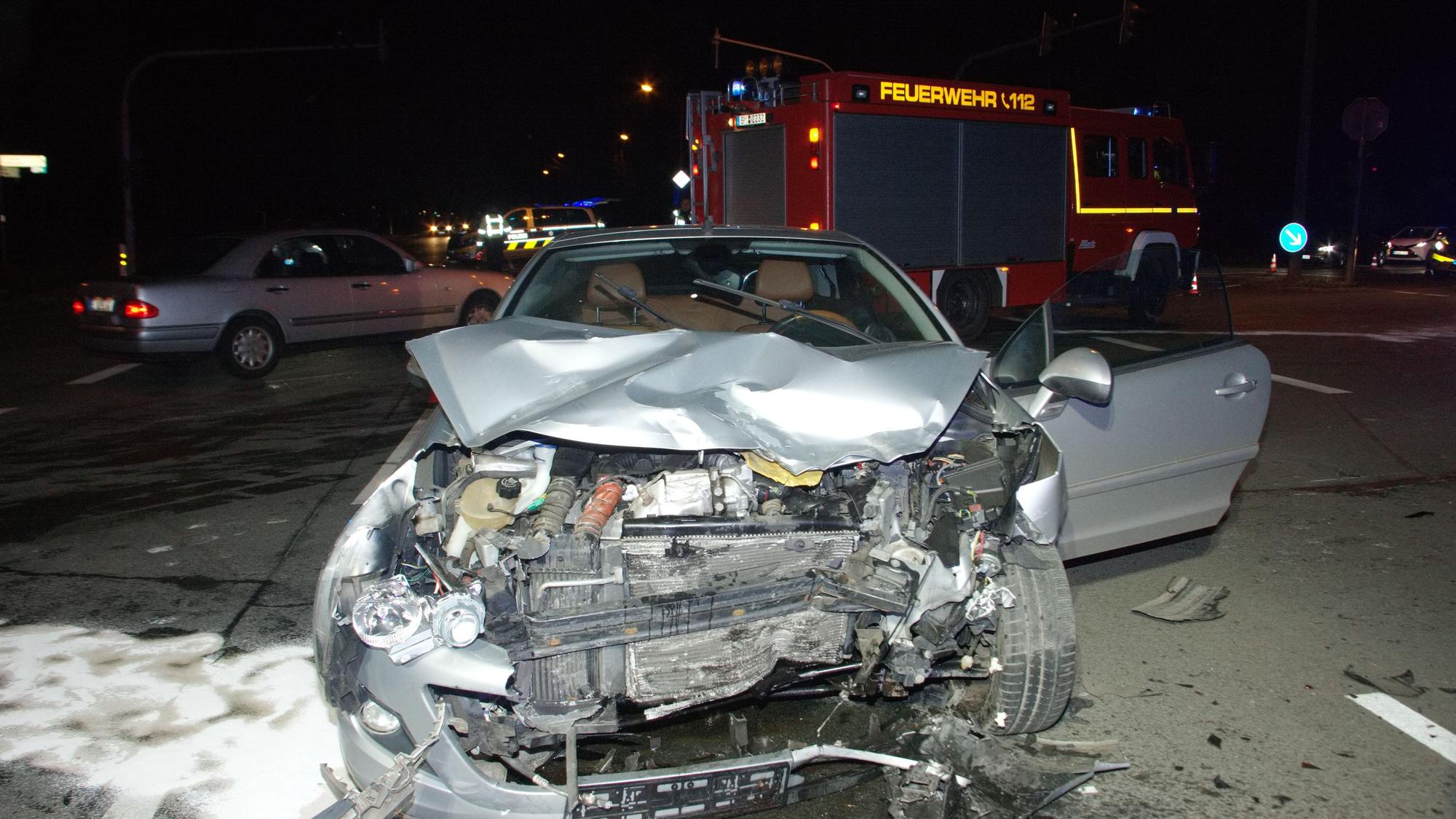Das Bild zeigt einen beschädigten Wagen vor einem Feuerwehrfahrzeug.