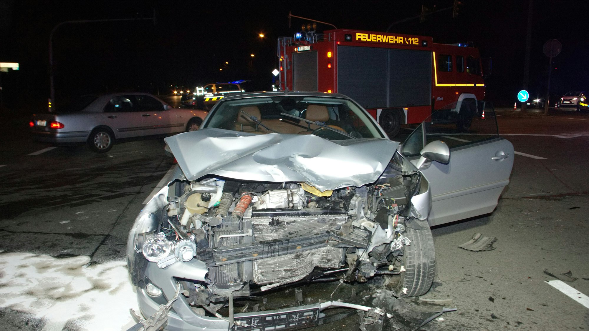 Das Bild zeigt einen beschädigten Wagen vor einem Feuerwehrfahrzeug.