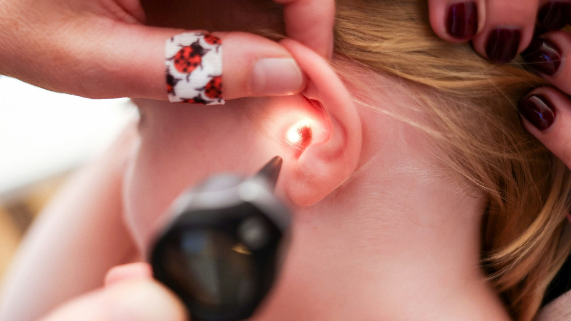 Mit einem Otoskop untersucht eine Kinderärztin ein Ohr eines Mädchens.