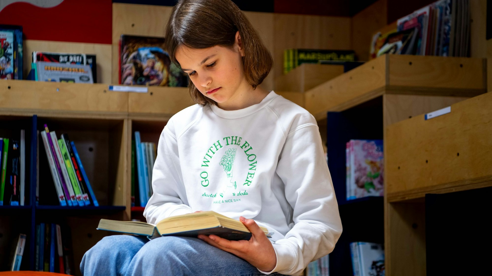 Das Bild zeigt Rosa, wie sie in einem Buch liest, das auf ihren Beinen liegt.