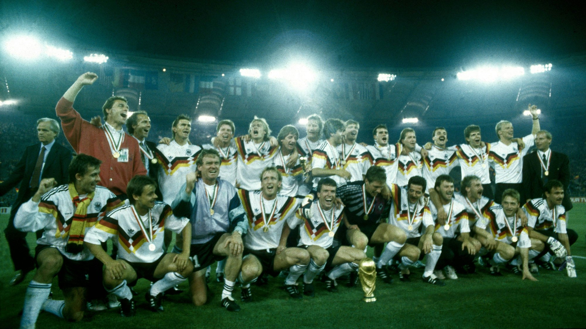 Weltmeisterschaft 1990. Die Deutsche Mannschaft mit WM Pokal nach dem Sieg im Finale am 8.7. in Rom, hi.v.li.: Holger Osieck, Franz Beckenbauer, Klaus Augenthaler, Stefan Reuter, Jürgen Klinsmann, Frank Mill, Guido Buchwald, Karl Heinz Riedle, Paul Steiner, Thomas Berthold, Andreas Köpke, Jürgen Kohler, Andreas Möller, Hansi Pflügler, Berti Vogts, vorn: Pierre Littbarski, Olaf Thon, Sepp Maier, Andreas Brehme, Lothar Matthäus, Bodo Illgner, Uwe Bein, Günter Hermann, Rudi Völler, Thomas Häßler, Raimond Aumann HM