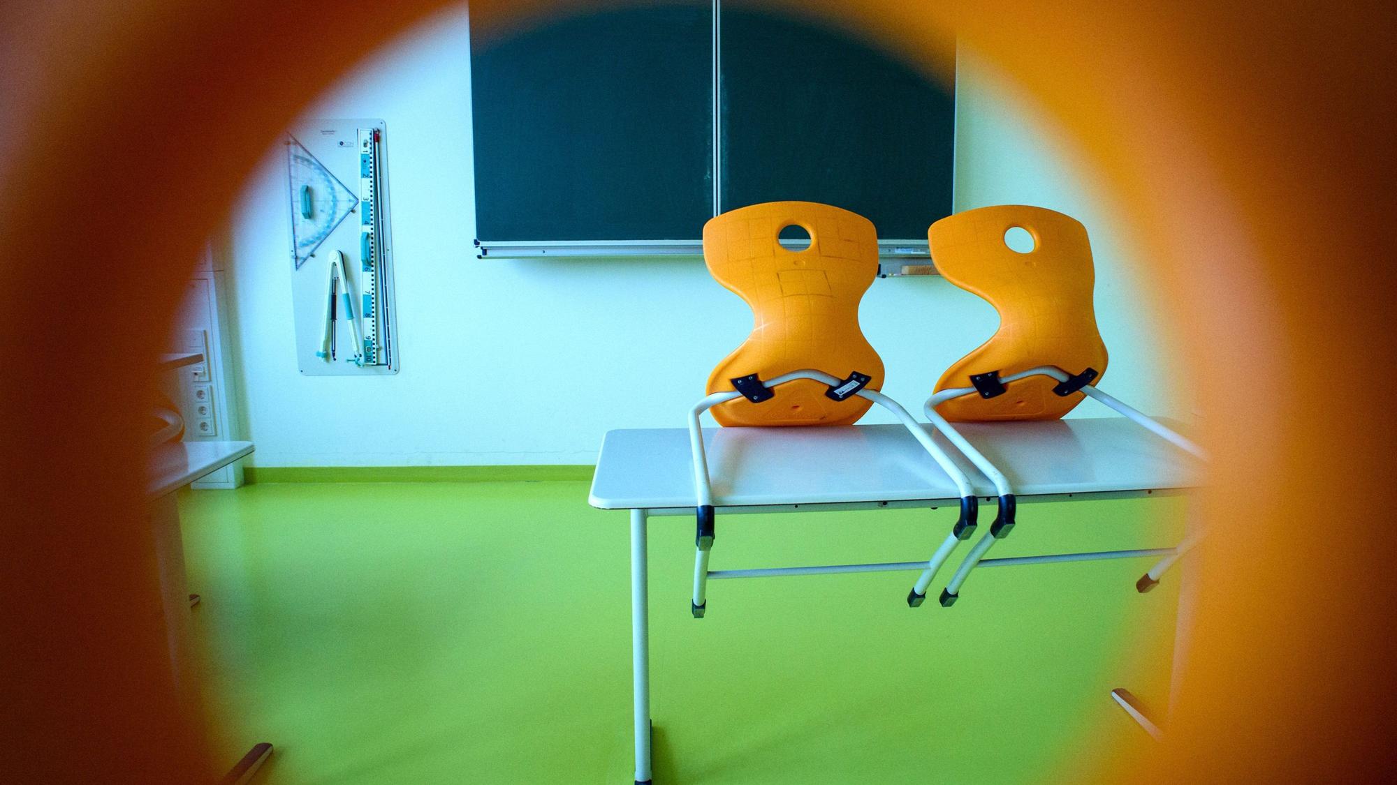 Stühle stehen in einem leeren Klassenzimmer einer Sekundarschule auf einem Tisch.