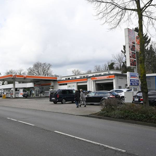 Zu sehen ist im Vordergrund die Fahrbahn, am Straßenrand befindet sich eine Tankstelle.