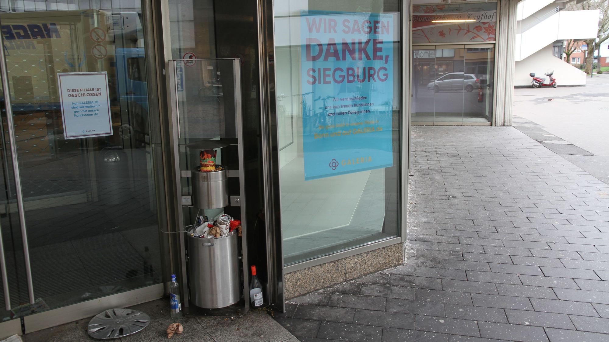 Ein überquellender Mülleimer neben dem Eingang eines geschlossenen Kaufhauses