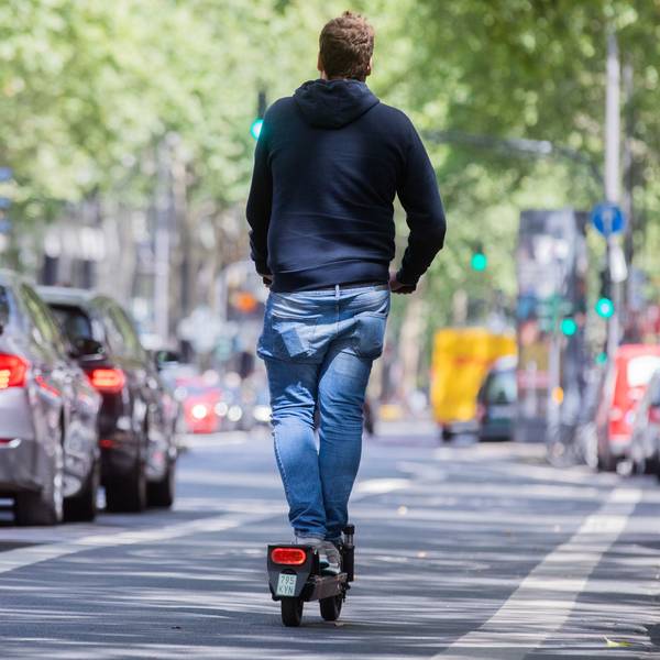 Ein Mann fährt auf dem Fahrradweg mit einem E-Scooter über den Kölner Ring.