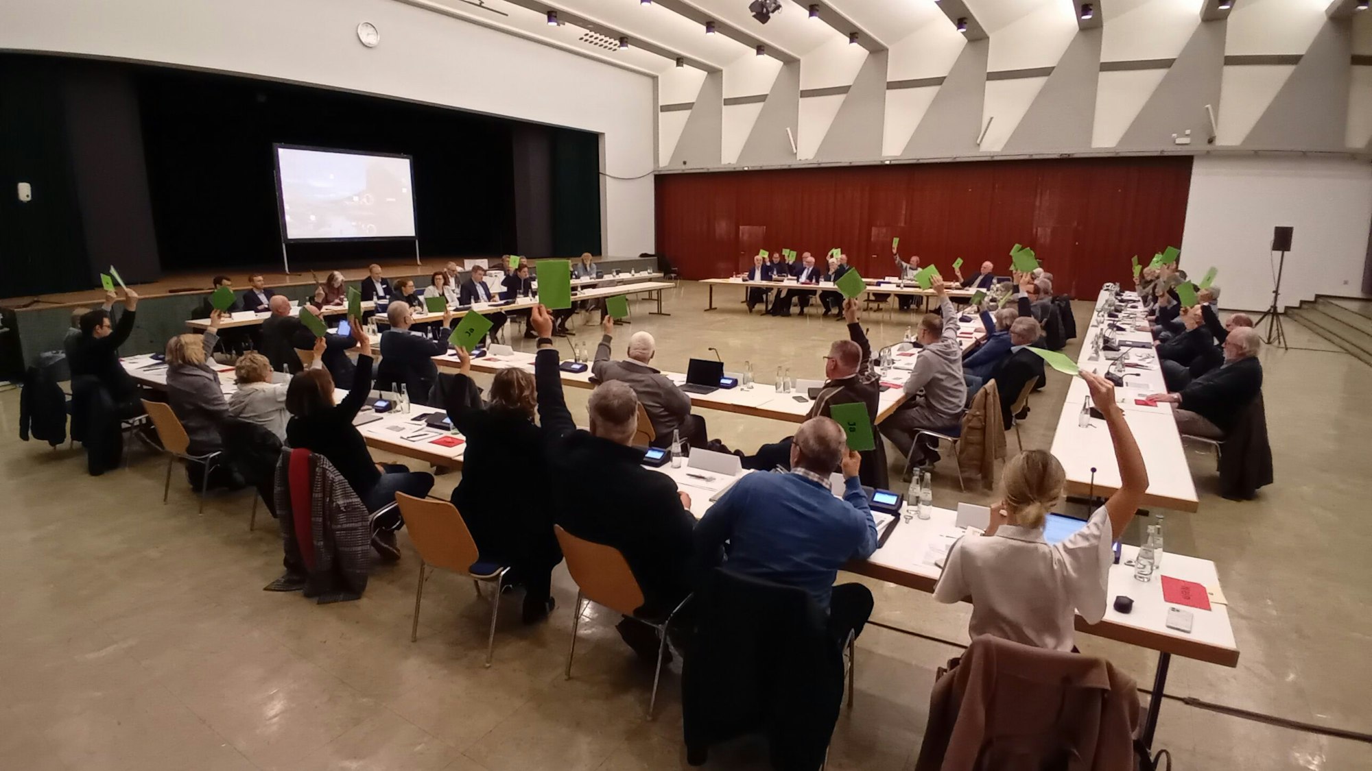 Die Stadtverordneten heben die grüne Zustimmungskarte.