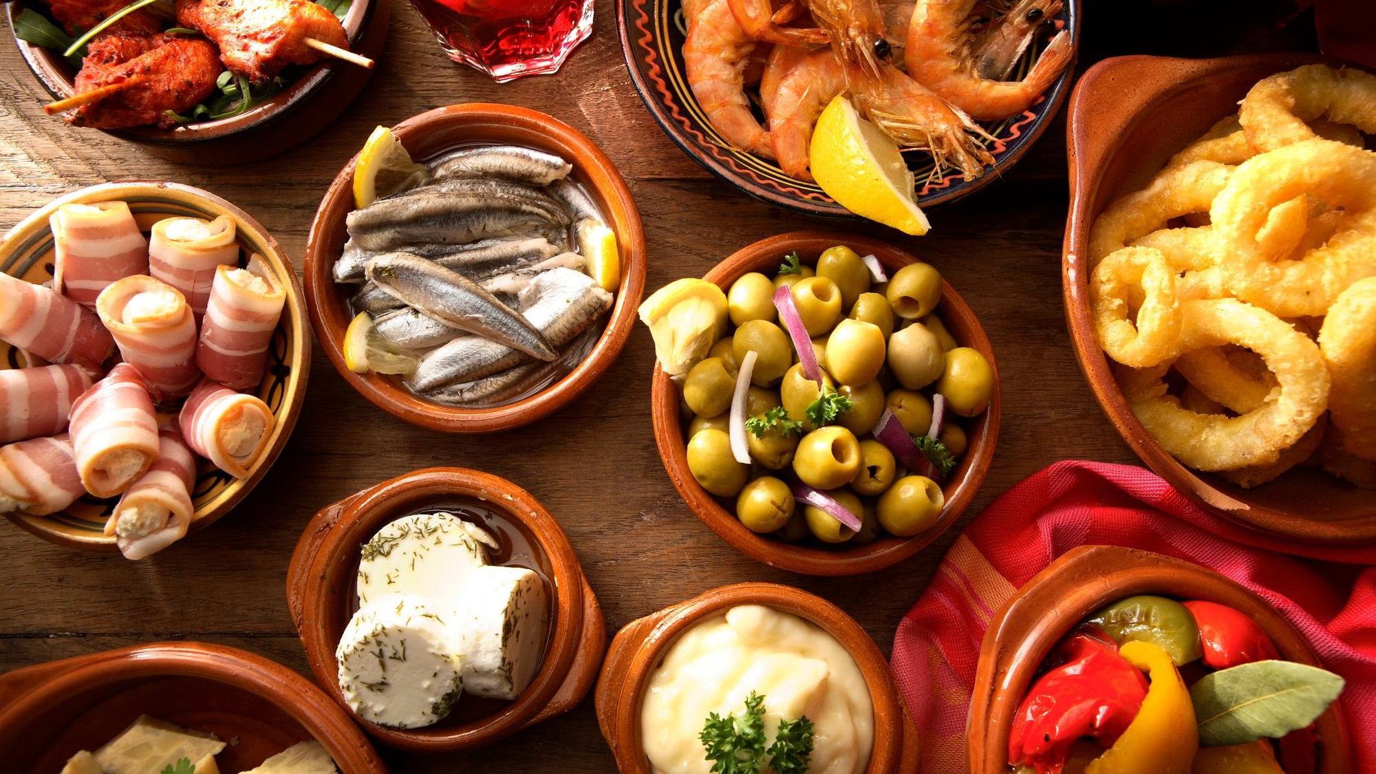 Viele kleine braune Schalen mit Oliven, Gambas und Boquerones.