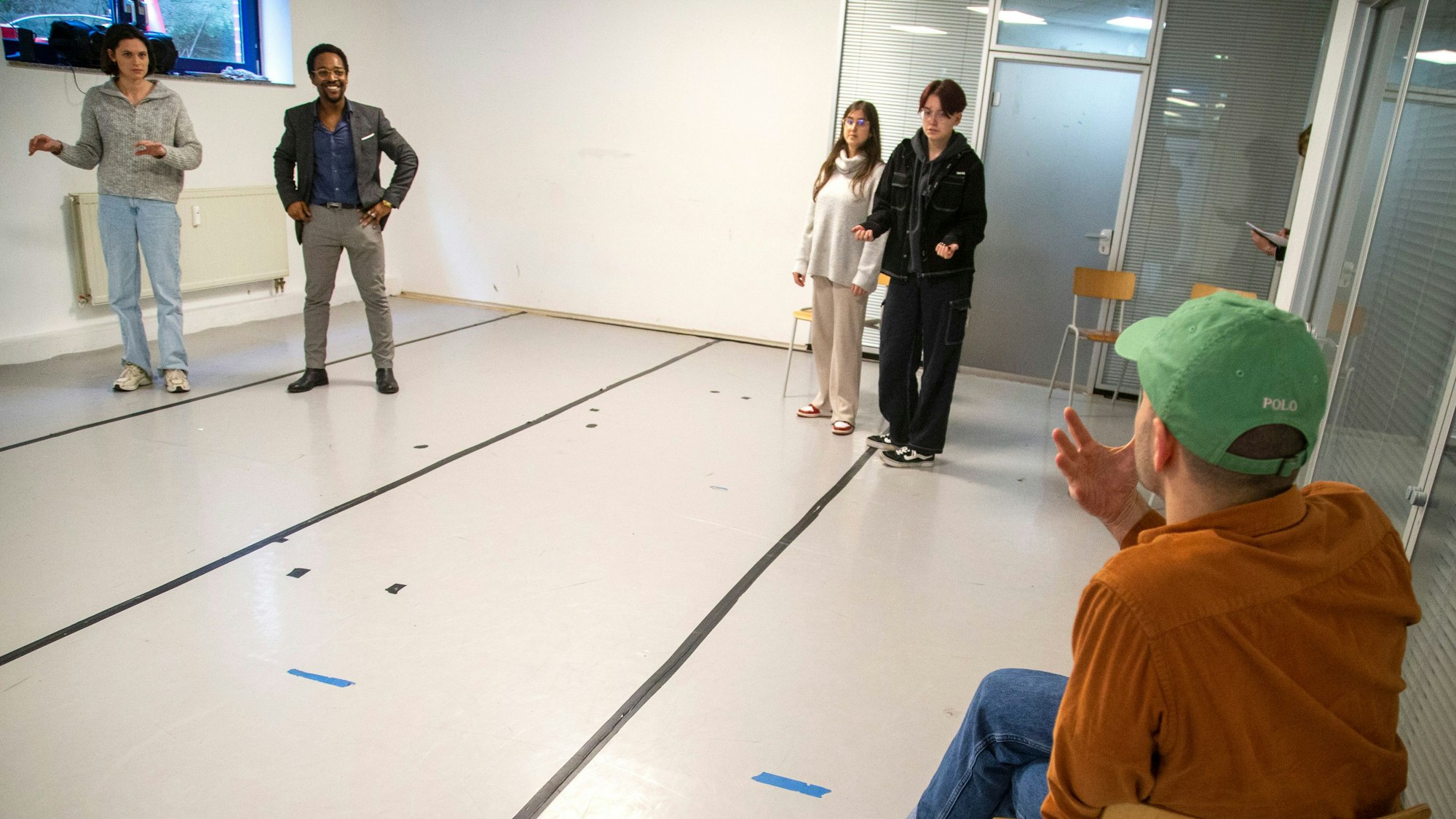 Ein gestikulierender Mann und junge Menschen, die zu ihm hinsehen.