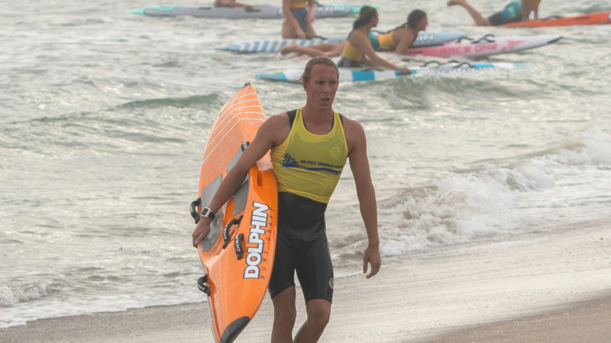 Lukas vom Eyser geht mit einem Kajak im Arm am Strand entlang
