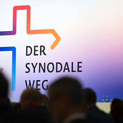 eilnehmer der Synodalversammlung sitzen vor dem Schriftzug „Der Synodale Weg“.