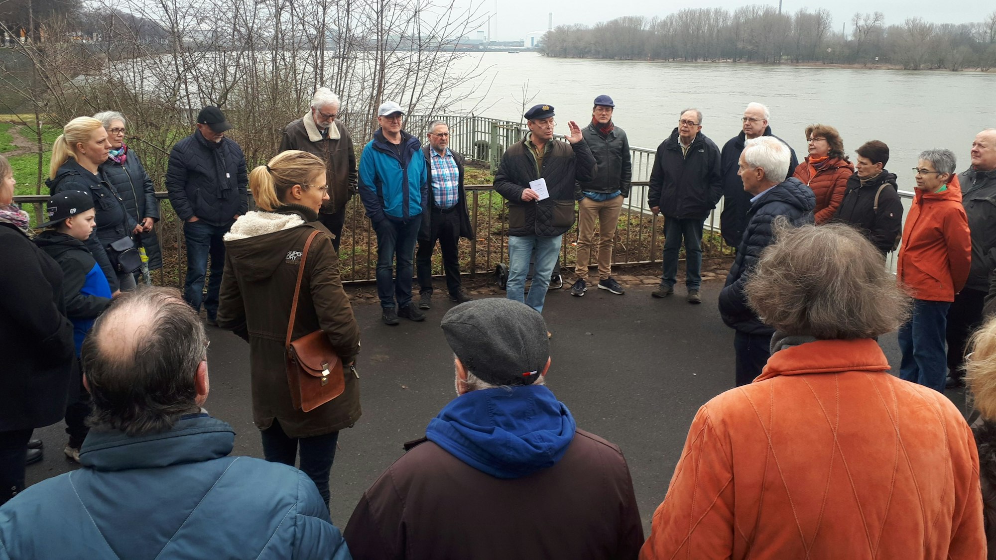 Menschen stehen im Halbkreis direkt am Rheinufer.