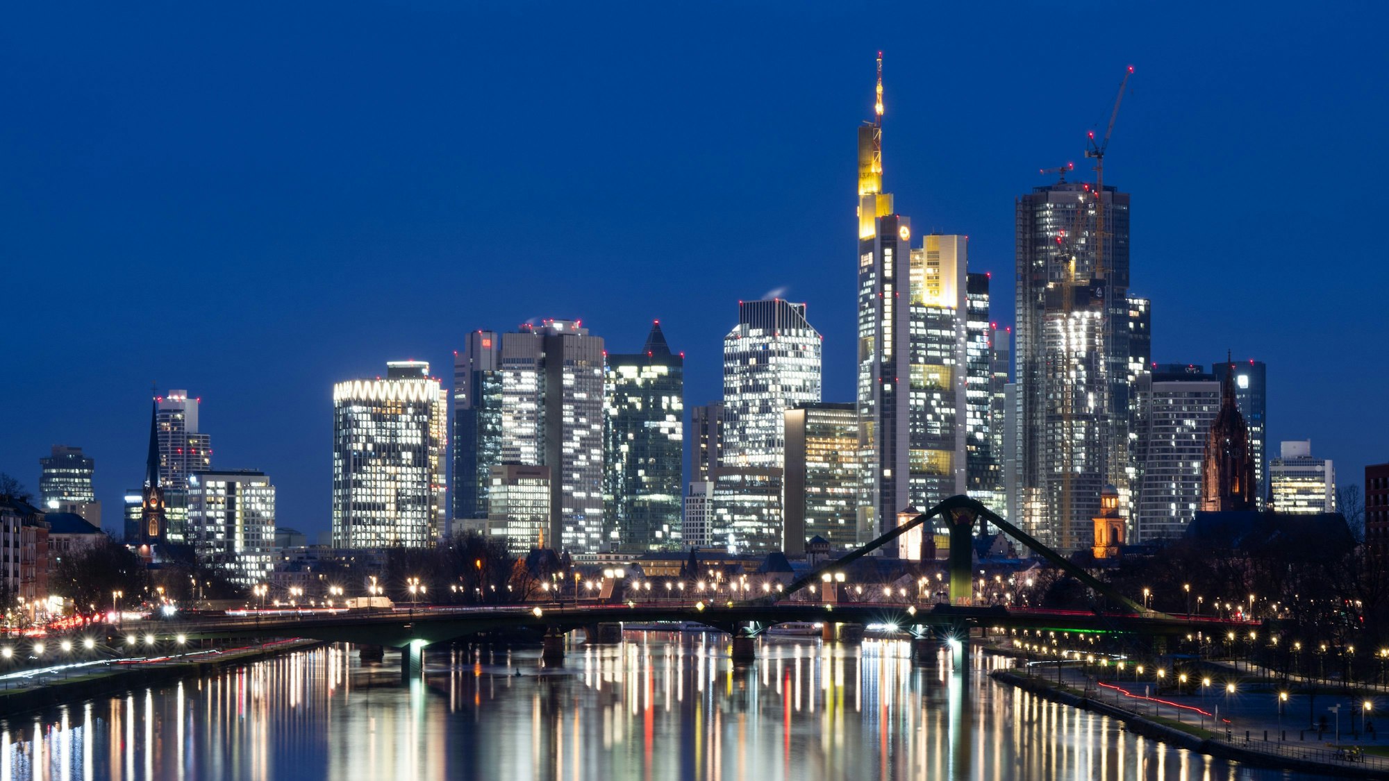 Die Lichter der Bankenskyline von Frankfurt am Main leuchten im letzten Licht des Tages.