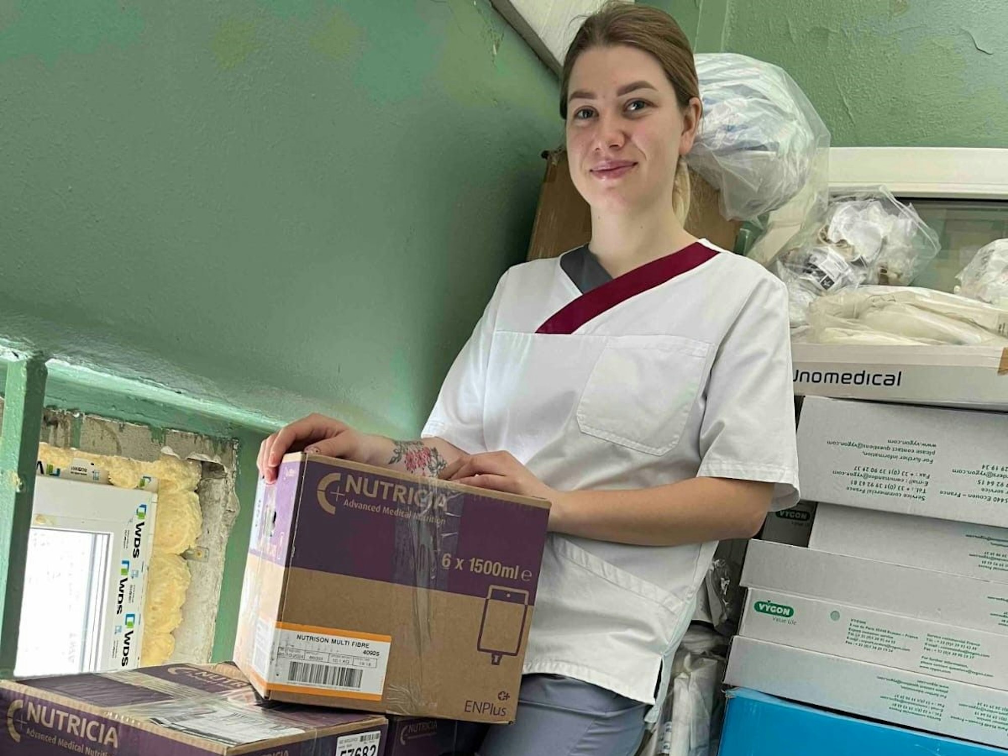 Eine junge Krankenschwester aus der Ukraine steht neben zehn Kisten mit Hilfsmitteln.