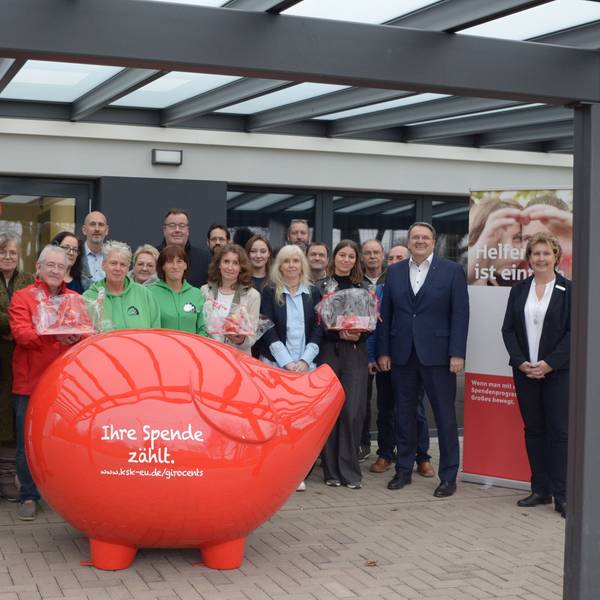 Vertreter von Vereinen und Kreissparkasse stehen für ein Gruppenfoto hinter einem überdimensionalen roten Sparschwein mit der Aufschrift „Ihre Spende zählt“.