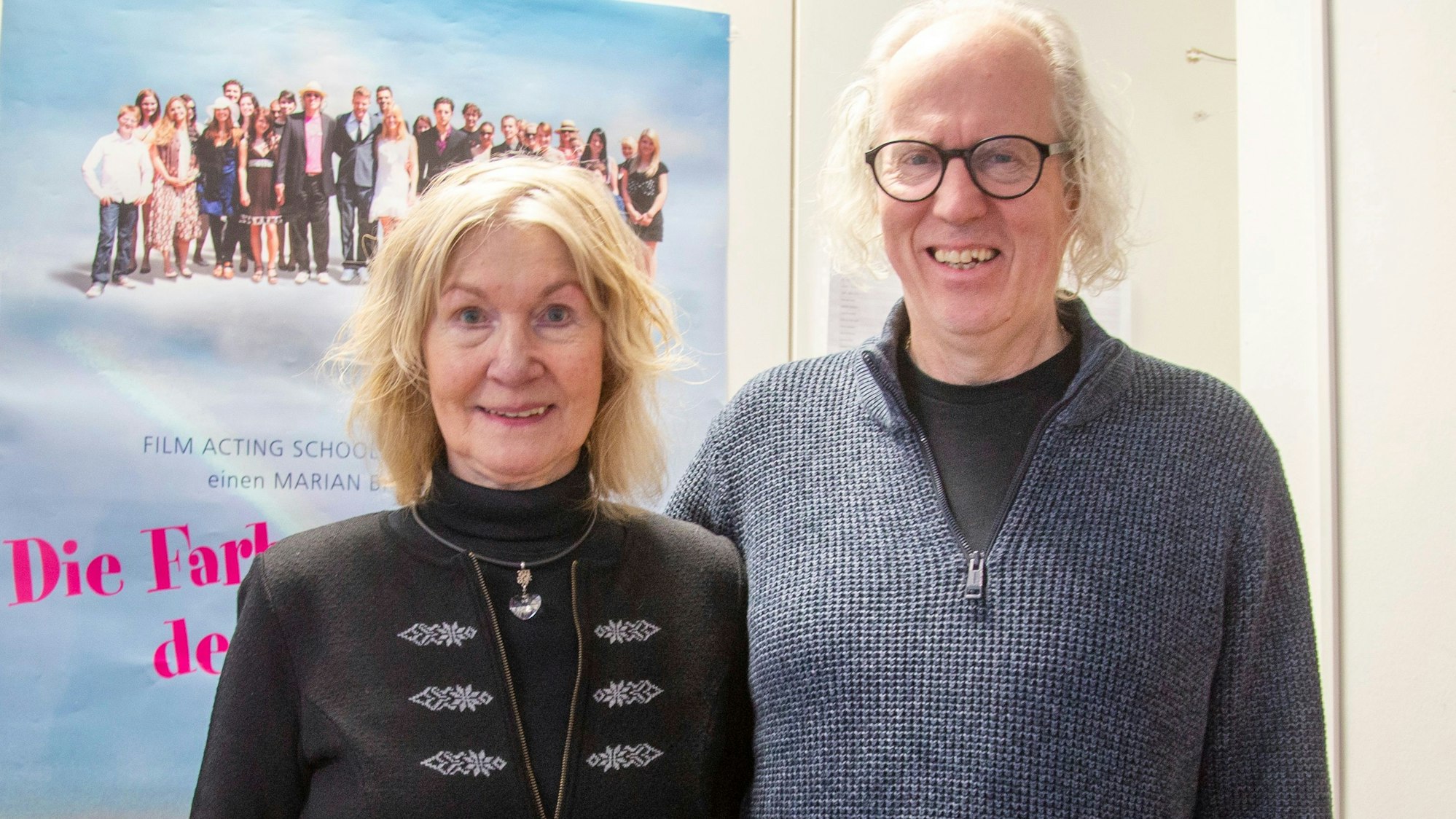 Eine Frau und ein Mann stehen vor einem Filmplakat.